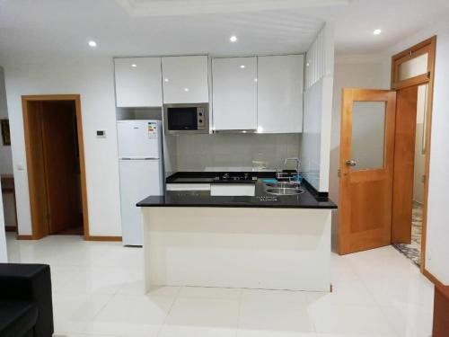 a kitchen with white cabinets and a black counter top at Apto Morabeza T2 Praia in Praia