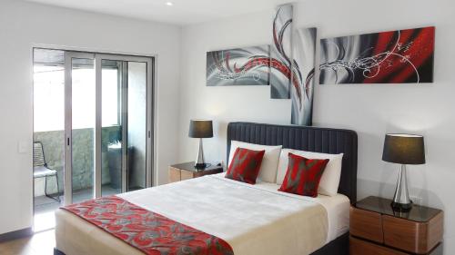a bedroom with a large bed with red pillows at Semaphore Splash Apartments in Port Adelaide