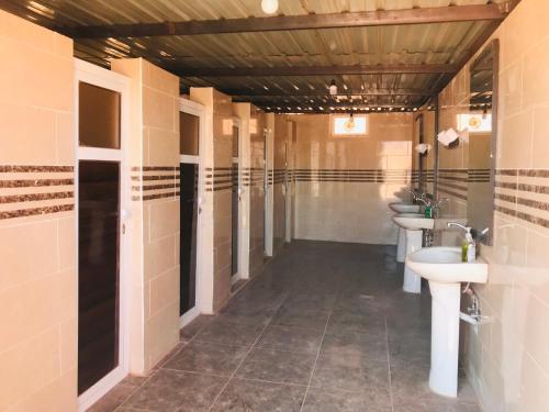 Baño con 3 lavabos y una fila de aseos en Red Mountain Camp, en Wadi Rum