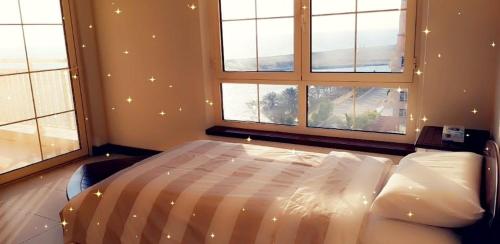 um quarto com uma cama num quarto com janelas em أزهار الكرز "سويت ملكي مطل على البحر" em King Abdullah Economic City