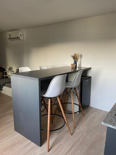 a black desk with white chairs in a kitchen at Estudio Loft in Mar del Plata