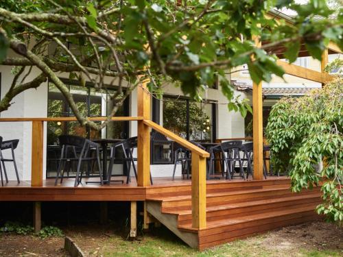 a wooden deck with black chairs on a house at Kyah in Blackheath