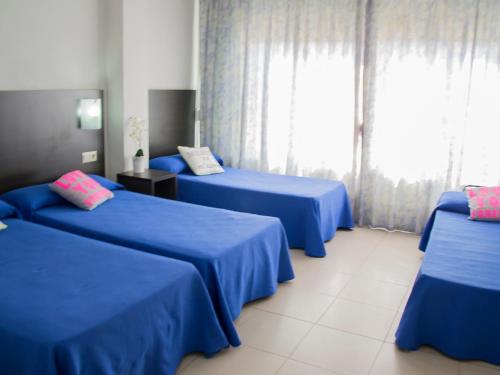 Habitación con 3 camas azules y ventana. en Hotel Safari, en Gandía