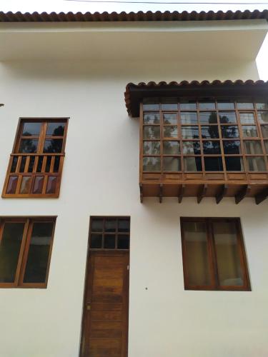 a white building with windows and a wooden door at Casa Agustina in Cusco