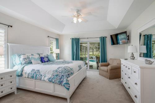 a white bedroom with a bed and a chair at Golf-Course Oasis in Naples