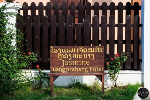a sign in the grass in front of a fence at Jasmine Luangprabang Hotel in Luang Prabang