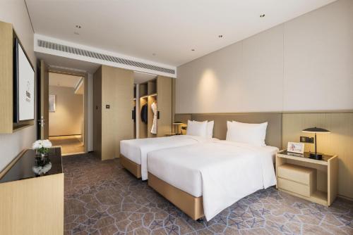 a large white bed in a hotel room at Modena by Fraser Nanjing in Nanjing