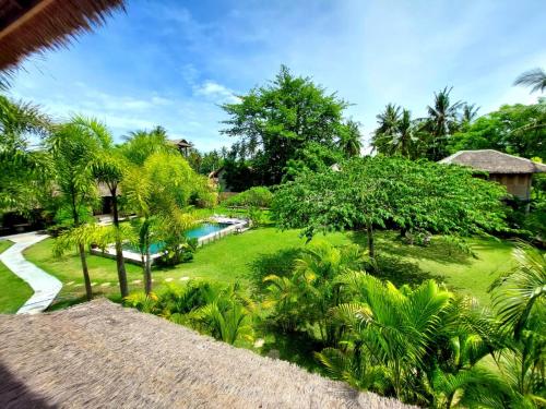 een uitzicht op een tuin met een zwembad bij Manusia Dunia Green Lodge in Gili Air