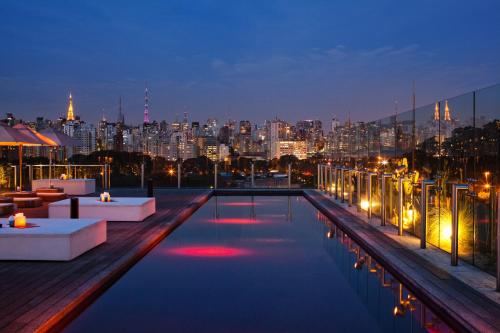 a rooftop pool with a view of the city at night at Hotel Unique in São Paulo