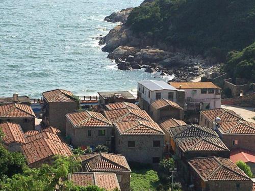 a group of houses with tile roofs next to the ocean at 雲台客棧民宿 in Nangan