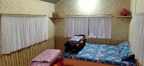 ein kleines Schlafzimmer mit einem Bett und einem Fenster in der Unterkunft Joe's Farm in Darjeeling