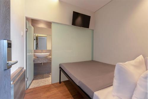 a bedroom with a bed and a bathroom with a sink at Livinn Juanda Airport Surabaya in Sidoarjo
