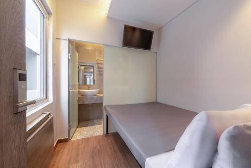 a small room with a bed and a bathroom at Livinn Juanda Airport Surabaya in Sidoarjo