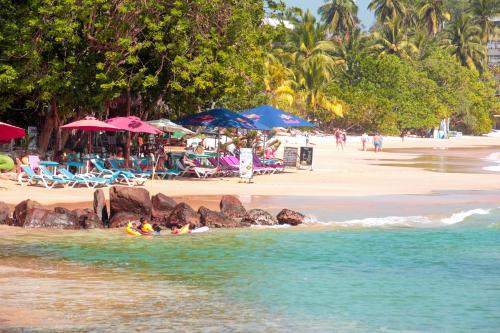 a beach with people in the water and umbrellas at Pearl Mirissa in Mirissa
