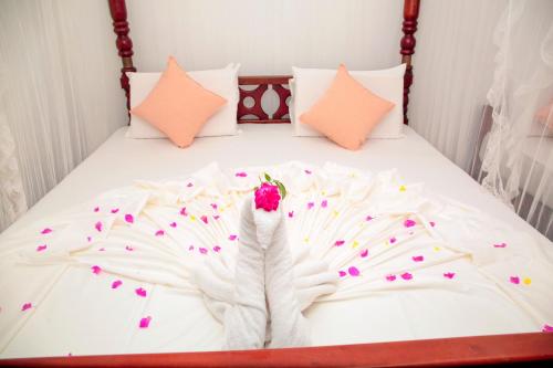 a bed with white sheets and a flower on it at Pearl Mirissa in Mirissa