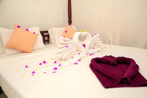 a white bed with pink and purple decorations on it at Pearl Mirissa in Mirissa