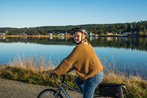 a woman riding a bike next to a lake at The Edenwild Boutique Inn in Lopez