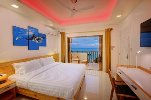 a bedroom with a bed and a balcony with the ocean at Luau Beach Inn, Maldives in Fulidhoo
