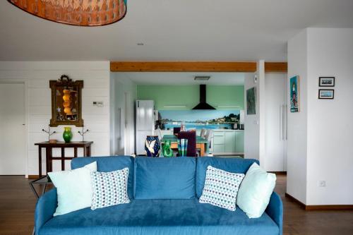 ein blaues Sofa im Wohnzimmer mit Küche in der Unterkunft À L'Accostage in Trégastel