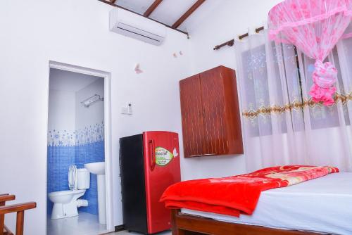 een slaapkamer met een rode koelkast en een badkamer bij Rashmi HomeStay in Balapitiya