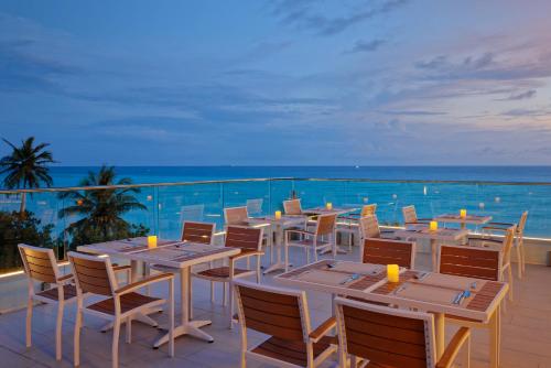 a restaurant with tables and chairs on a balcony at Luau Beach Inn, Maldives in Fulidhoo