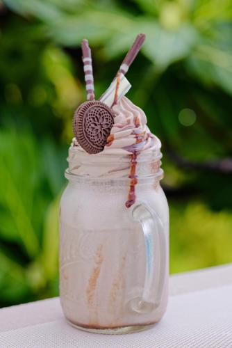 a mason jar with a cookie on top of whipped cream at Luau Beach Inn, Maldives in Fulidhoo