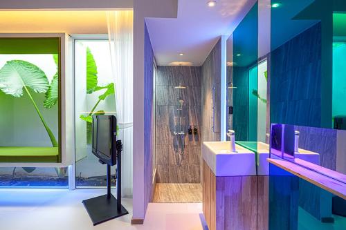 a bathroom with a sink and a shower and a tv at INNLUXPHUKET in Ban Laem Hin