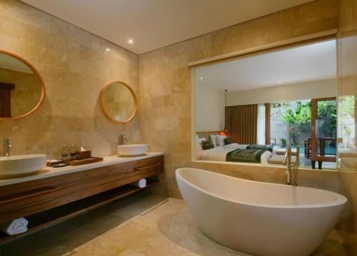 a bathroom with a tub and two sinks and a bedroom at JAPA Suites & Villas in Ubud