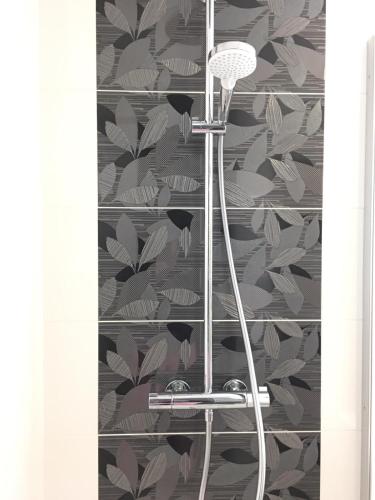 La salle de bains est pourvue d'une douche et de papier peint à feuilles. dans l'établissement La Cite des Pins - Piscine chauffee, à Les Sables-dʼOlonne
