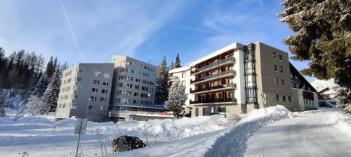 a building in the snow next to a road at Strbske Pleso Smrek Penthouse Apartment in Štrbské Pleso