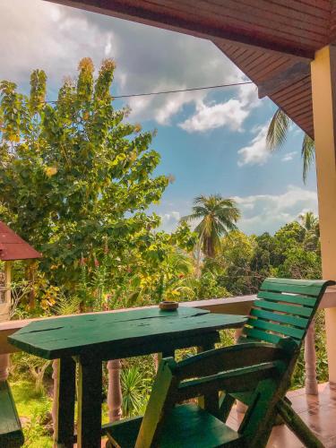 a green table and a chair on a porch at Tanouy Garden in Baan Khai