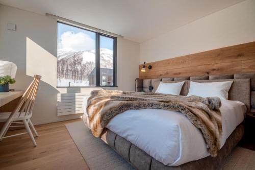 a bedroom with a bed and a desk and a window at Koa Niseko in Niseko