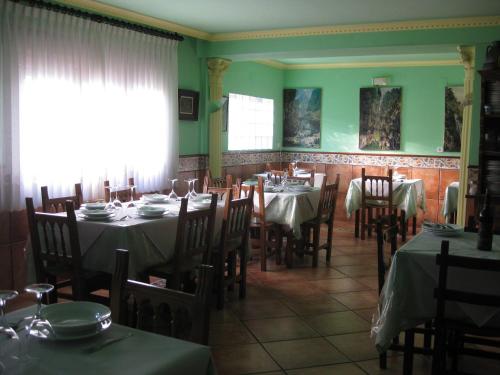 uma sala de jantar com mesas e cadeiras e paredes verdes em Hostal el Duje em Tielve