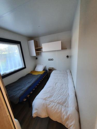 Habitación pequeña con 2 camas y ventana en Mobil Home 2022 les charmettes 3 Chambres 40m2, en Les Mathes
