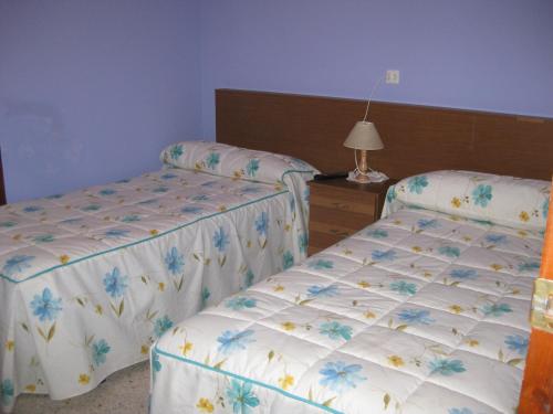 2 camas individuales en un dormitorio con lámpara en Hostal el Duje en Tielve