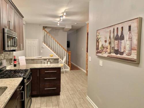 een keuken met een schilderij van wijnflessen aan de muur bij Upscale 2BD/1.5BA townhome mins to JHH & downtown in Baltimore