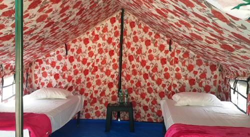 Habitación con 2 camas y pared roja. en The Raajas - Camp & Resorts en Rishīkesh