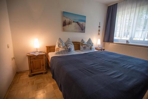 a bedroom with a large bed with a blue blanket at Pension Hinter der Düne in Juliusruh