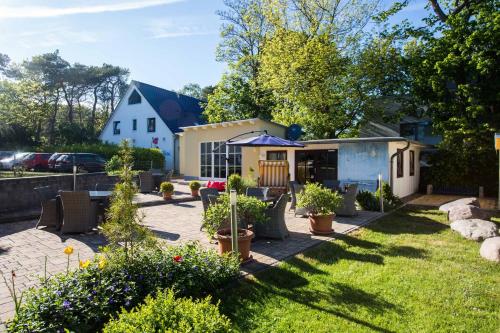 a backyard with chairs and plants and a house at Pension Hinter der Düne in Juliusruh