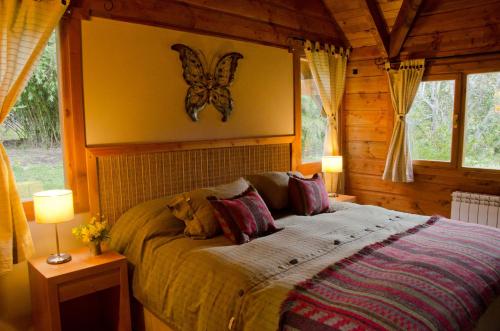 ein Schlafzimmer mit einem Bett mit einem Schmetterling an der Wand in der Unterkunft Tillka - Casas de Montaña in Villa La Angostura