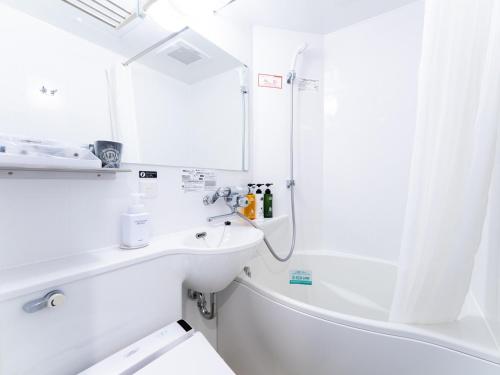 uma casa de banho branca com um lavatório e um chuveiro em APA Hotel Fukuoka Tenjin Nishi em Fukuoka
