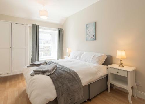 a bedroom with a bed with a night stand and a window at Potters Retreat in Alnwick