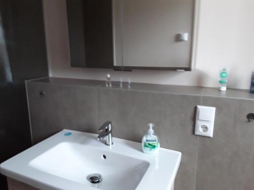 La salle de bains est pourvue d'un lavabo blanc et d'un miroir. dans l'établissement Gästezimmer Herzogenrath, à Herzogenrath