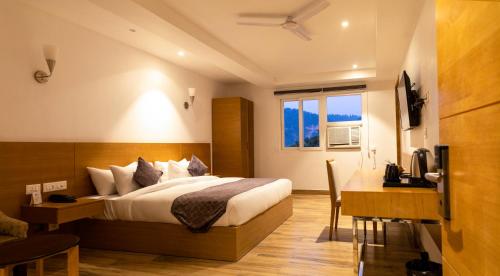 een slaapkamer met een bed, een bureau en een raam bij TRIBHAV Corbett Bliss-Jim Corbett in Rāmnagar