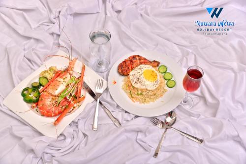 a table with two plates of food with an egg and shrimp at Nuwara Wewa Holiday Resort in Anuradhapura