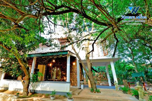 a building with a tree in front of it at Nuwara Wewa Holiday Resort in Anuradhapura
