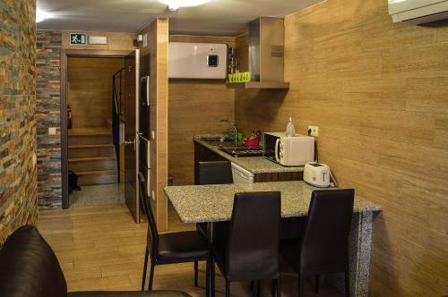a kitchen with a table with chairs and a microwave at Apartamentos Turísticos Toledo in Toledo