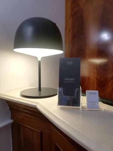 a black lamp sitting on a desk with a book at BB Hotels Smarthotel Bailey's in Rome