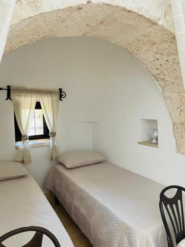 a bedroom with two beds and a window at TRULLO FERNANDO in San Michele Salentino