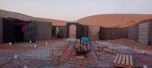 a room with tables and chairs in a desert at Merzouga Camp and Hostel in Merzouga